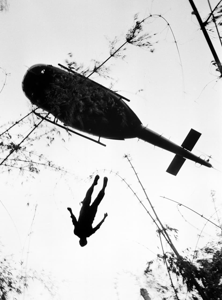 The body of a U.S. paratrooper killed in action in the jungle near the Cambodian border is lifted up to an evacuation helicopter in War Zone C, May 14, 1966. The zone, encompassing the city of Tay Ninh and the surrounding area north of Saigon, was the site of the Viet Cong’s headquarters in South Vietnam. (Henri Huet/AP)