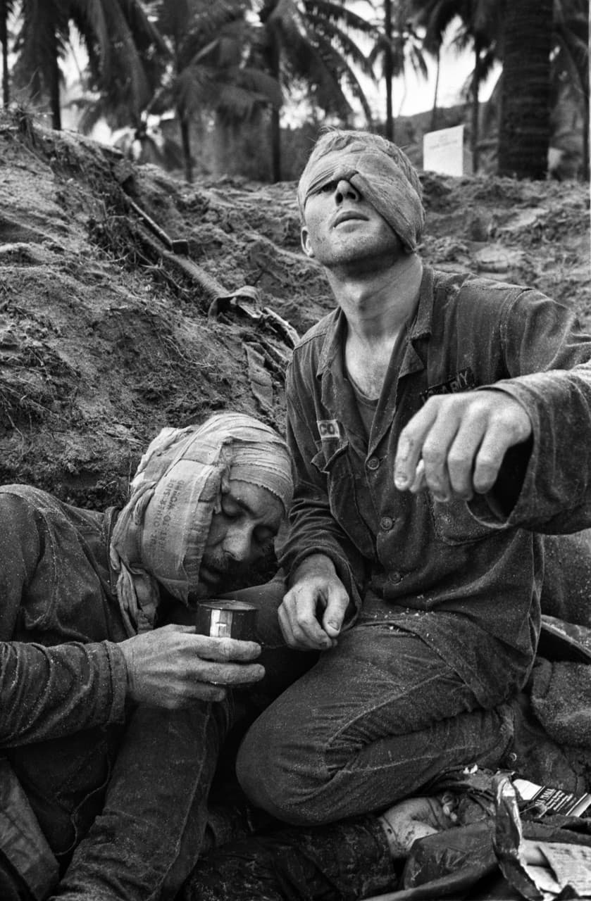 Medic Thomas Cole of Richmond, Virginia, looks up with his one unbandaged eye as he continues to treat wounded S.Sgt. Harrison Pell of Hazleton, Pennsylvania, during a firefight, January 30, 1966. The men belonged to the 1st Cavalry Division, which was engaged in a battle at An Thi, in the Central Highlands, against combined Viet Cong and North Vietnamese forces. This photo appeared on the cover of Life magazine, February 11, 1966, and photographer Henri Huet’s coverage of An Thi received the Robert Capa Gold Medal from the Overseas Press Club. (Henri Huet/AP)