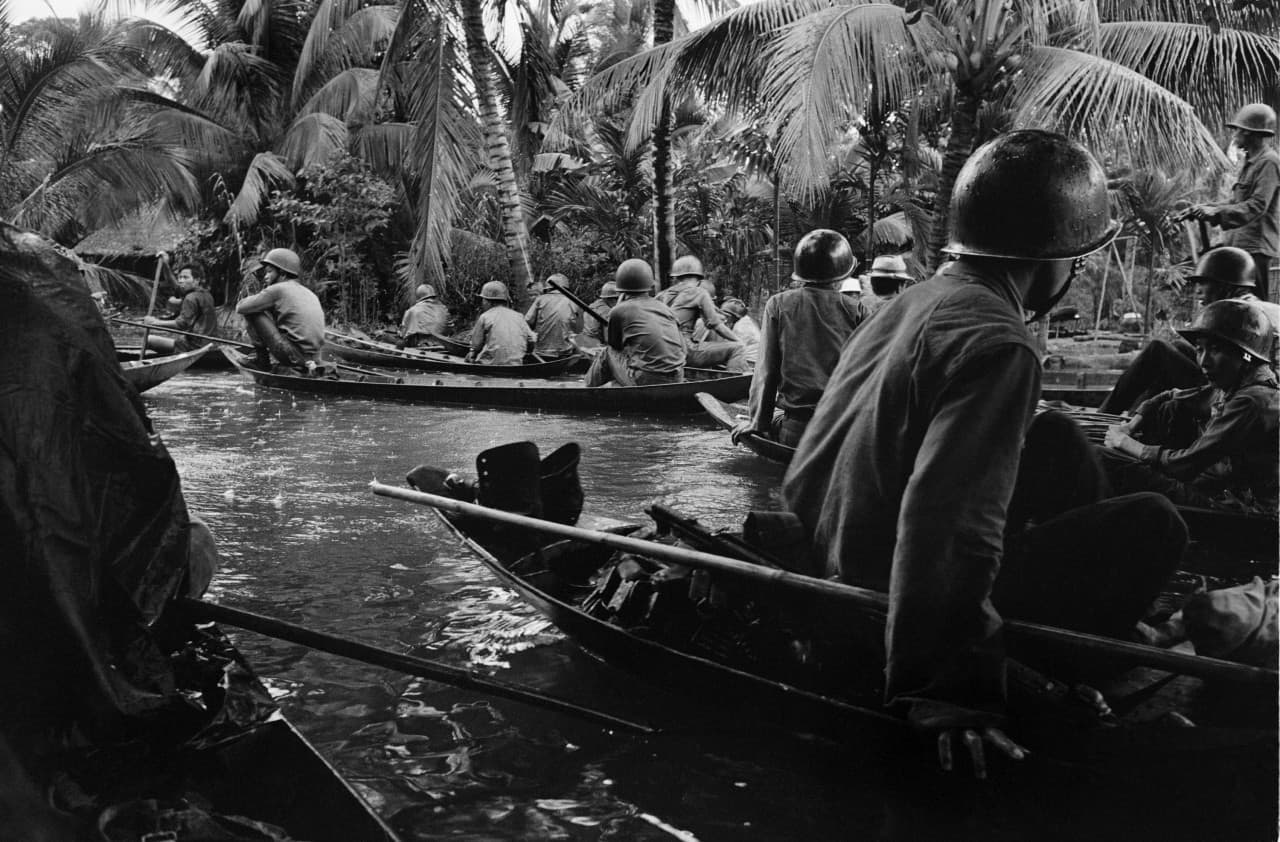 Caught in a sudden monsoon rain, part of a company of about 130 South Vietnamese soldiers moves downriver in sampans during a dawn attack on a Viet Cong camp, January 10, 1966. Several guerrillas were reported killed or wounded in the action thirteen miles northeast of Can Tho, in the flooded Mekong Delta. (Horst Faas/AP)