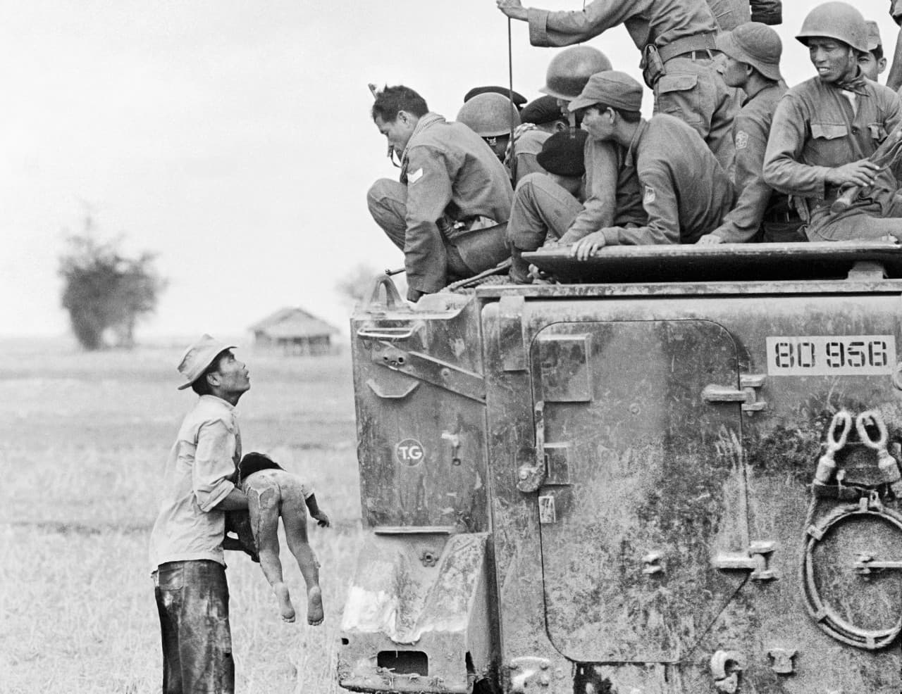 A distraught father holds the body of his child as South Vietnamese Rangers look down from their armored vehicle, March 19, 1964. The child was killed as government forces pursued guerrillas into a village near the Cambodian border. From the portfolio by photographer Horst Faas that received the 1965 Pulitzer Prize for Photography. (Horst Faas/AP)