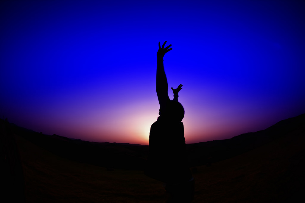 A silhouette stretches his arms in happiness. (August Brill/Flickr)