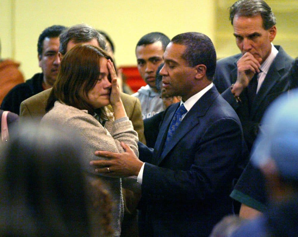 A worker from Michael Bianco Inc., who gave only her first name, Tiadoro, and said she is from Honduras, is comforted by then-Gov. Deval Patrick as he meets with workers and their families at a church in New Bedford on March 8, 2007. (David Goldman/AP)