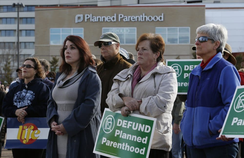 Participants in an anti-abortion rally hold signs and listen to a speaker in front of Planned Parenthood of the Rocky Mountains in Denver in February. (Brennan Linsley/AP)