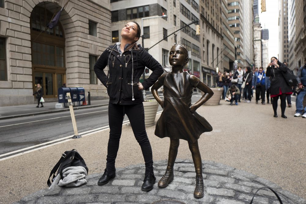 A woman strikes a pose with the &quot;Fearless Girl&quot; statue on Wednesday, International Women's Day. (Mark Lennihan/AP)