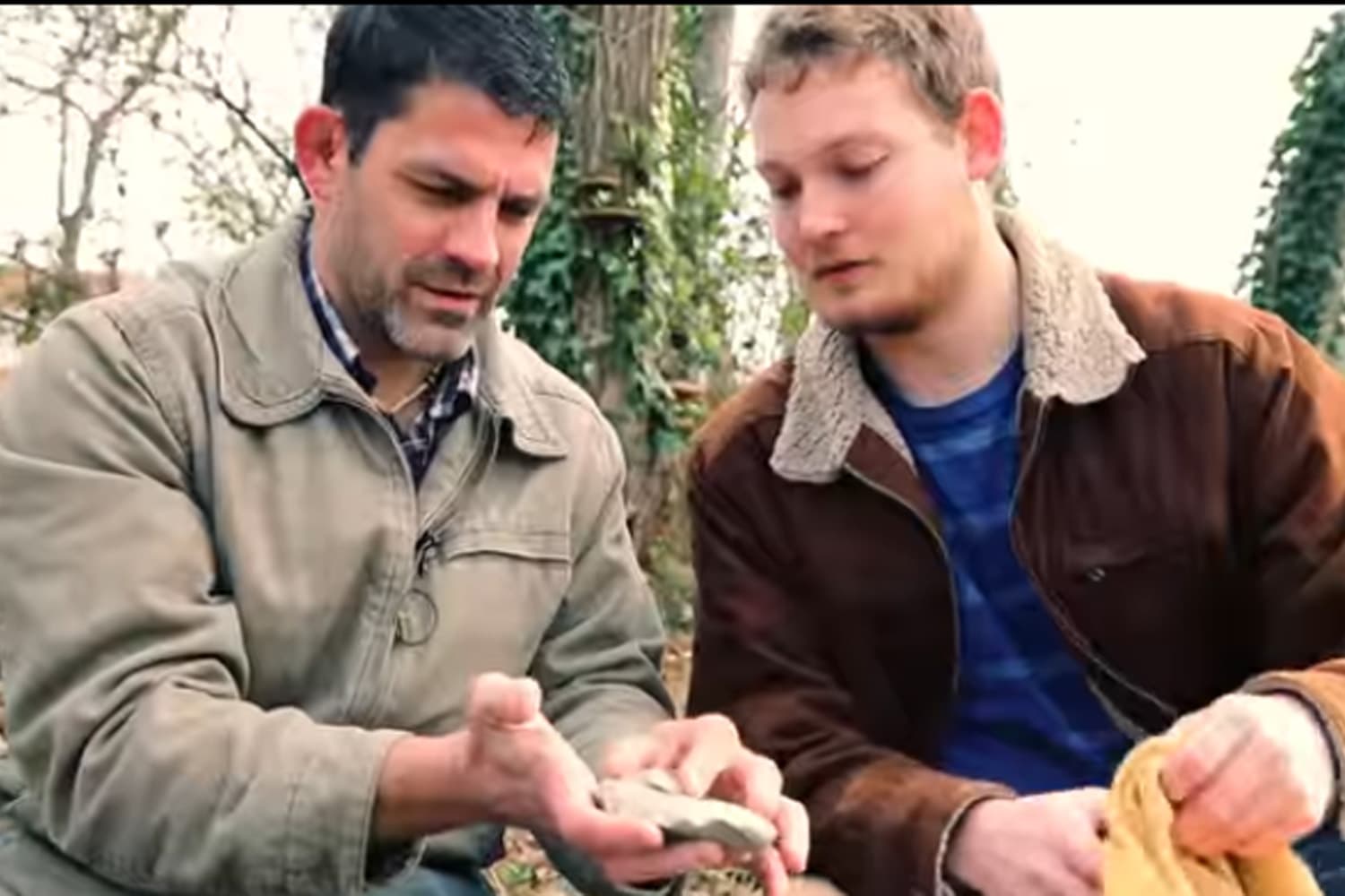 Bill Schindler, an associate professor of anthropology instructs former student Mike Whisenant, class of 2016, in primitive carving techniques in a still from a video filmed at Washington College. (Courtesy Washington College)