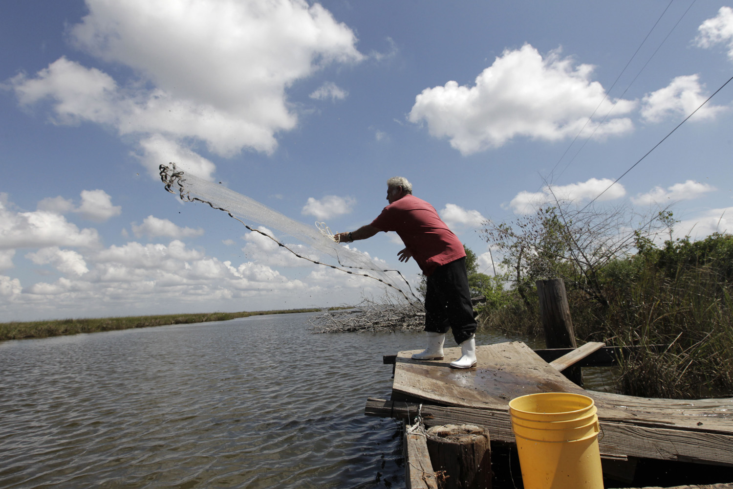 In this file photo, Edison Dardar, an American Indian, tosses a cast net for shrimp on the edge of Pointe- aux-Chenes wildlife management area, in Isle de Jean Charles, La. (Gerald Herbert/AP)