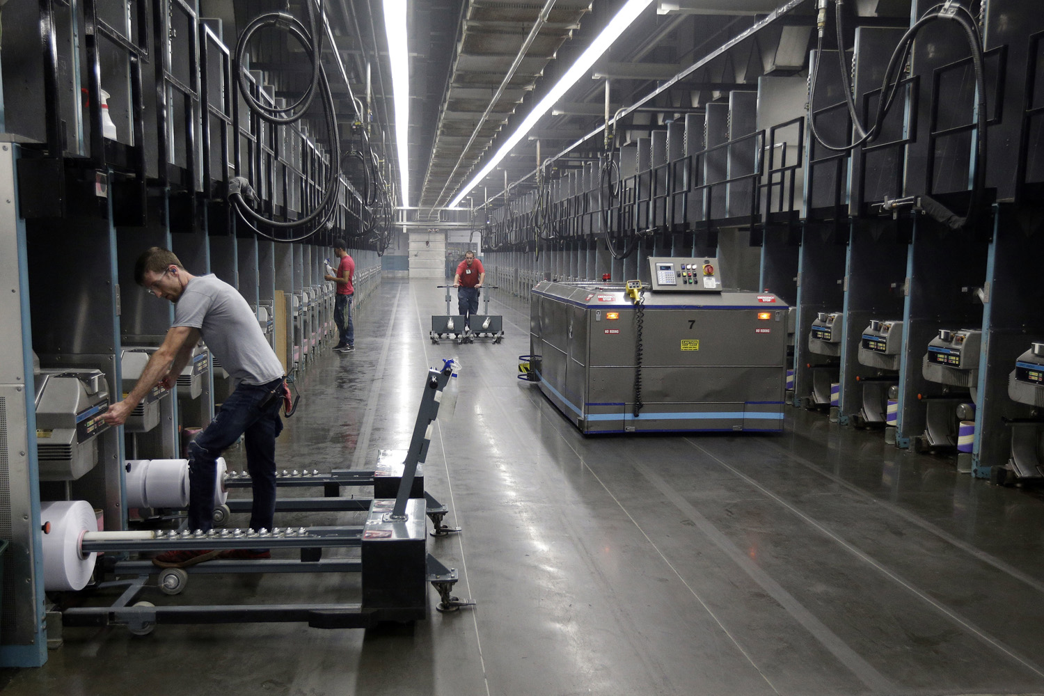 Workers exchange spools of thread as a robot picks up thread made from recycled plastic bottles at the Repreve Bottle Processing Center, part of the Unifi textile company in Yadkinville, N.C. (Chuck Burton/AP)
