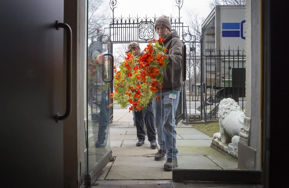 Corey Roche, 21, leads a group of four staffers carrying a string of nasturtiums through a doorway into the Gardner Museum. (Robin Lubbock/WBUR)