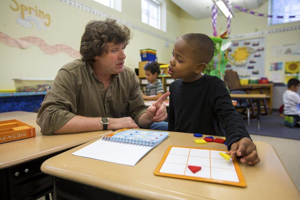Lawrence Elementary first grade teacher Jonathan Norwood guides Shamar Morris on how to play the geometric puzzle game Meta-Forms. (Jesse Costa/WBUR)