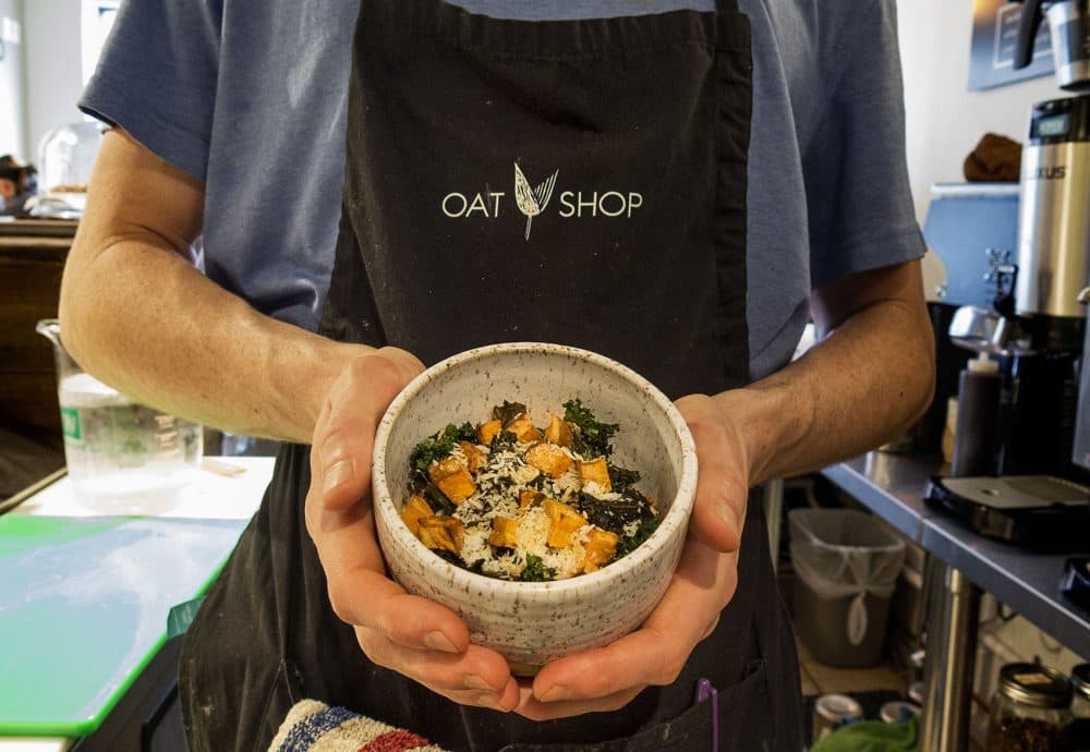 Oat Shop founder Alan Donovan holds the savory sweet potato coconut curry bowl that’s topped with toasted coconut, roasted garlic, sweet potato and kale chips. (Andrea Shea/WBUR)