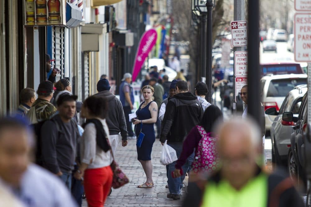 A woman stops on Broadway's crowded sidewalk. City residents say fears of being caught in federal immigration raids have some people staying out of public spaces to avoid arrest. (Jesse Costa/WBUR)