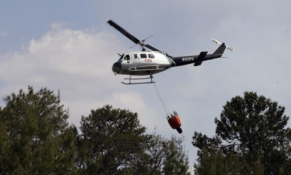 A Florida Division of Forestry helicopter drops a bucket of water on a wildfire April 11, 2017, in Hudson, Florida. (Chris O'Meara/AP)