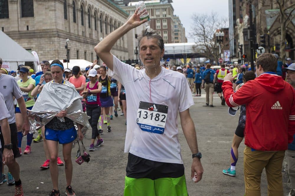 Sylvain Lanthier, of Montreal, dumps a bottle of water over his head after finishing the marathon. (Jesse Costa/WBUR)