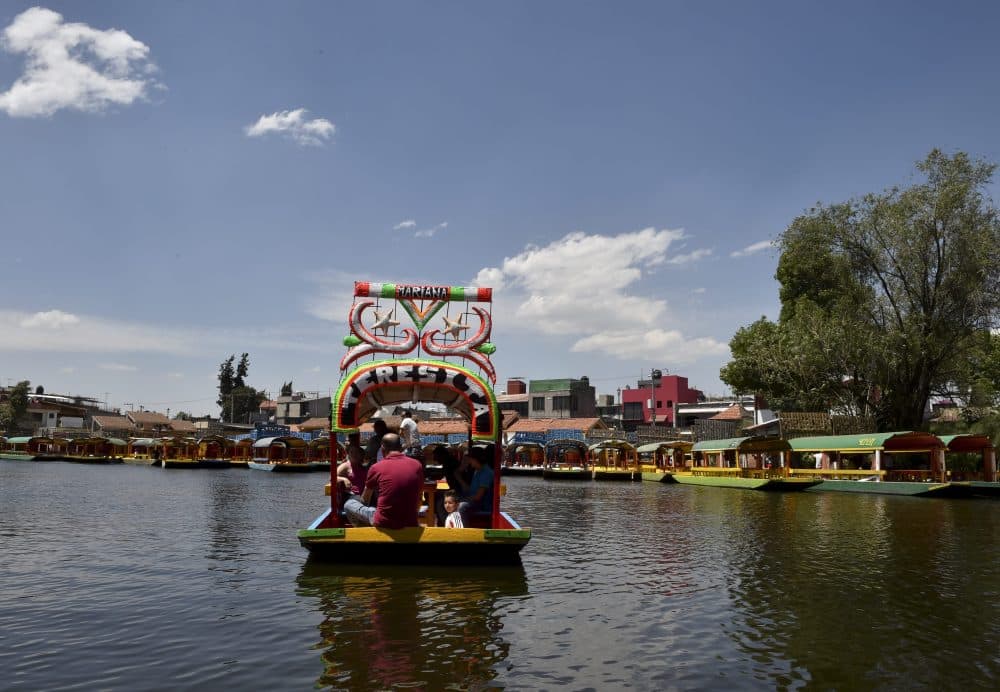 A rower and tourists are seen on board of a moored &quot;trajinera,&quot; a traditional flat-bottomed river boat, at Xochimilco natural reserve in Mexico City on April 1, 2016. (Yuri Cortez/AFP/Getty Images)