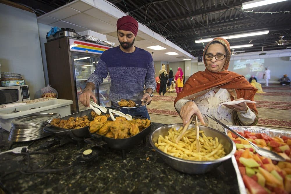 Kanwar Singh, left, fills a plate with food at the Sikh temple in Everett. (Jesse Costa/WBUR)