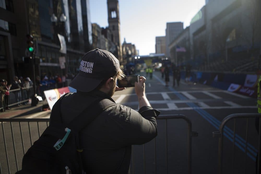Brian Marcou takes a photo of the finish line from at Exeter Street before the first marathoners reach it. (Jesse Costa/WBUR)