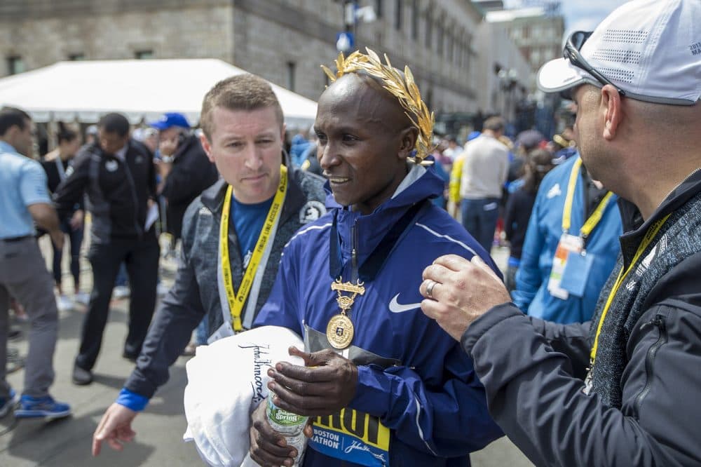 Marathon race officials escort Geoffrey Kirui to the medical tent after his win. (Jesse Costa/WBUR)