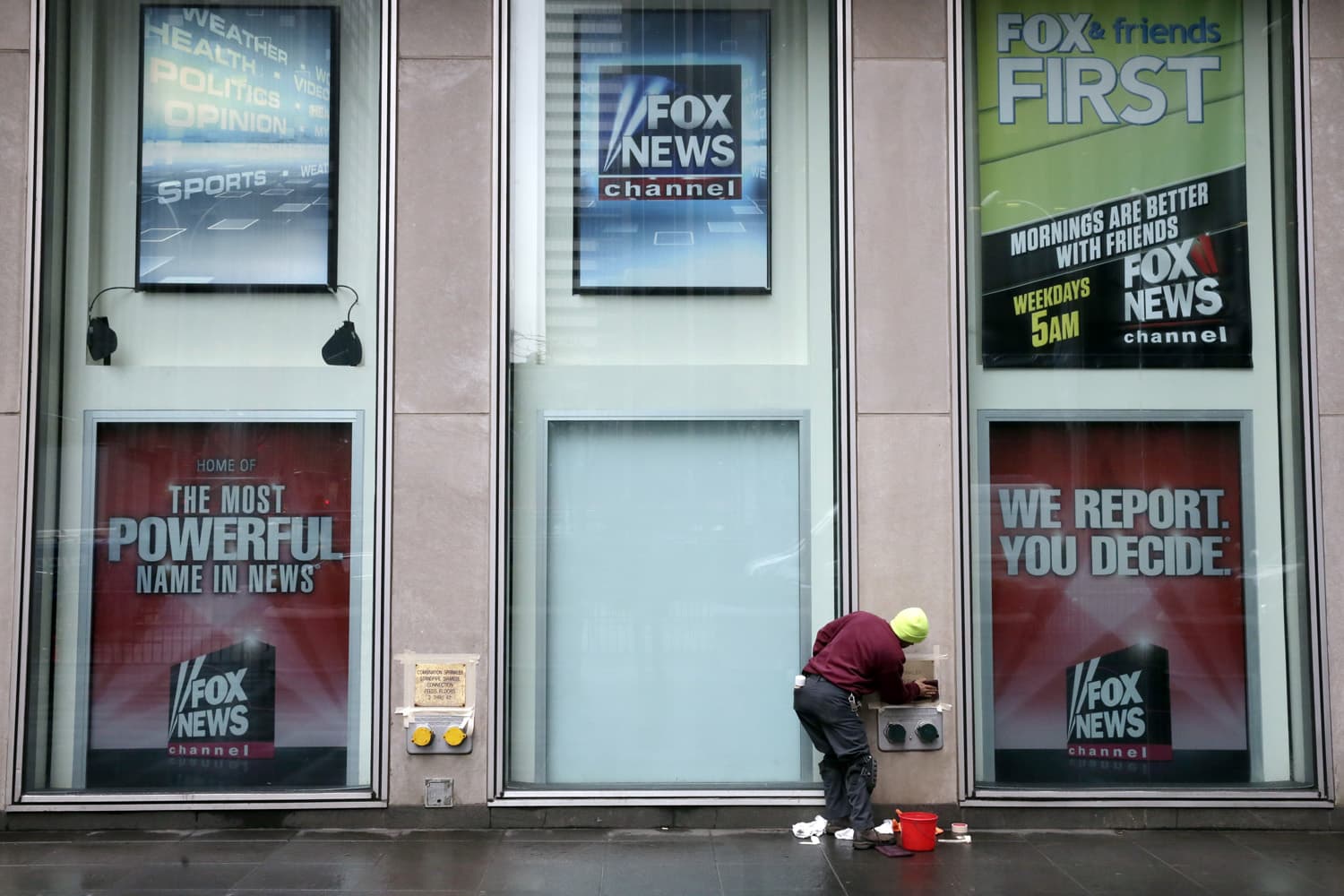 A worker cleans a sign outside the Fox television studios, where a poster of Bill O'Reilly has been removed, in New York. (Richard Drew/AP)
