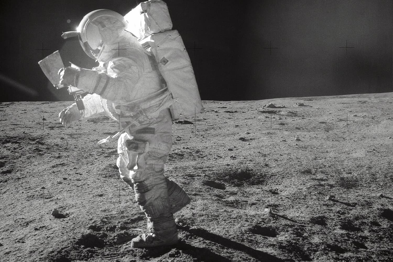 Astronaut Edgar D. Mitchell, Apollo 14 Lunar Module pilot, moves across the lunar surface as he looks over a traverse map during extravehicular activity (EVA). (NASA)