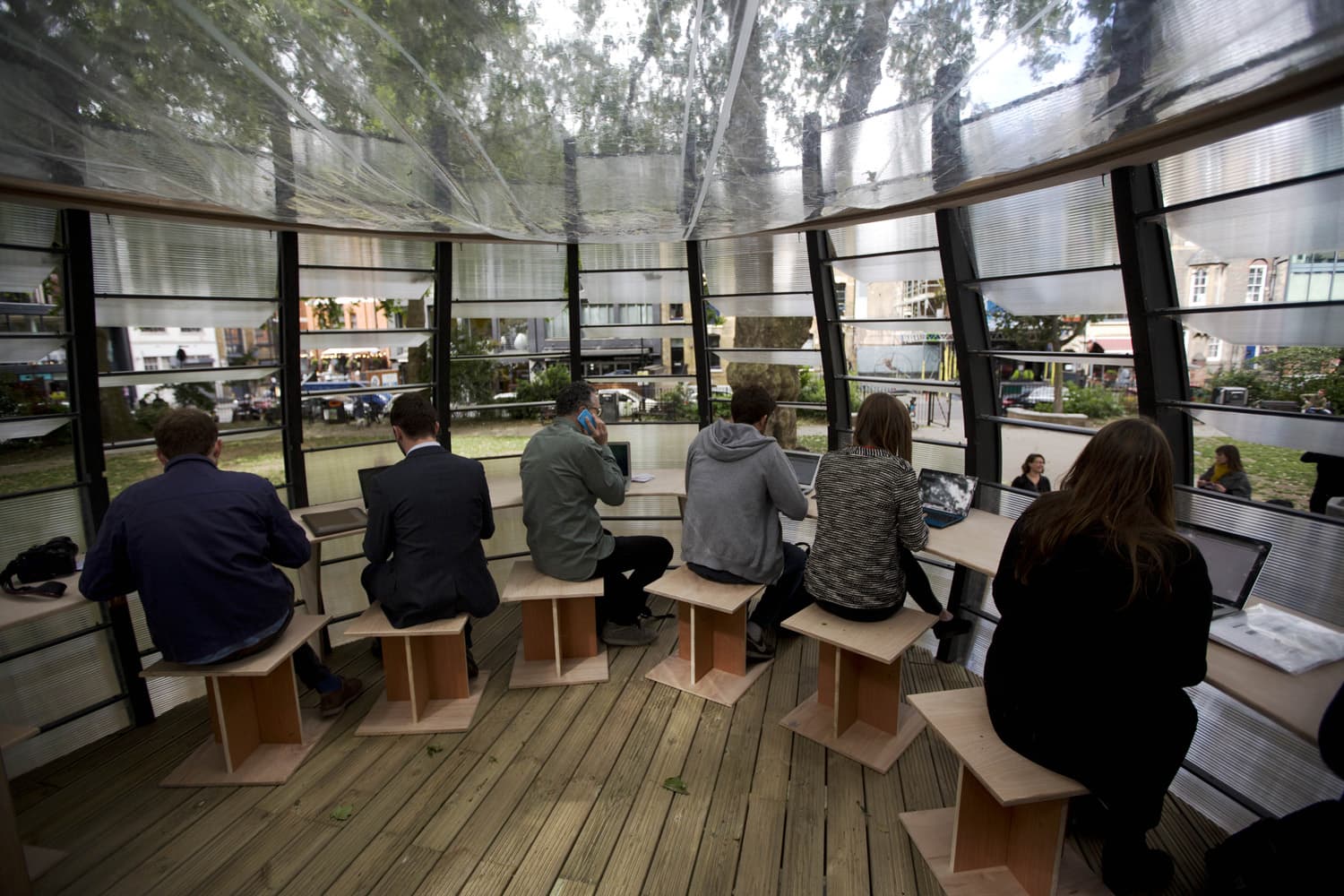 People pose for the media and work during an event to launch TREExOFFICE, a prototype pop-up tree office, in Hoxton Square, London. (Matt Dunham/AP)