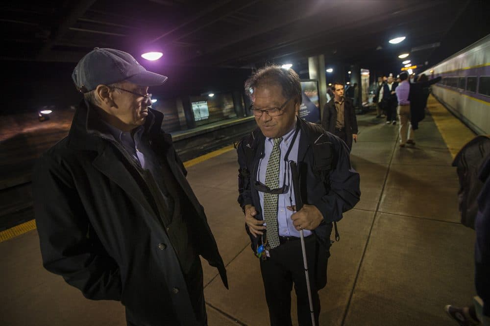 David Hill, left, meets Blair Wong on the platform in Back Bay station to help guide him. (Jesse Costa/WBUR)