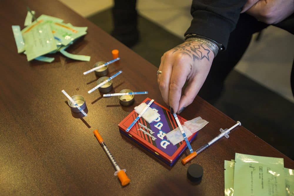 Jess Tilley demonstrates how to test empty heroin bags. (Jesse Costa/WBUR)