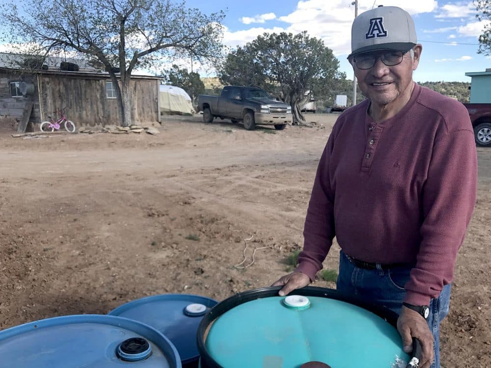 Percy Deal on the Navajo reservation, with 55-gallon drums he uses to haul water to his home. (Peter O'Dowd/Here &amp; Now)