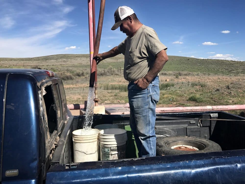 John Davis fills water buckets in the back of his truck at a well at the Kayenta coal mine, where locals come to get water for their homes. (Peter O'Dowd/Here &amp;amp; Now)