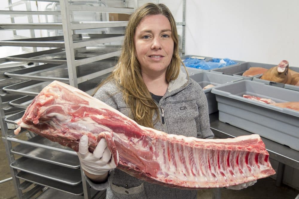 Kate Stillman with a loin butchered on-site at her farm in Hardwick. (Andrea Shea/WBUR)