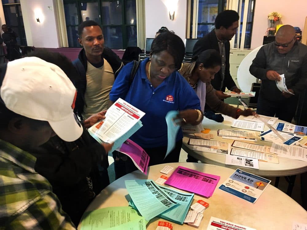 Attendees at a community forum collect handouts with information on immigration services. Many members of Boston’s Haitian community have been worried about the fate of their Temporary Protected Status which enables them to live and work in the U.S. The Trump administration announced Monday Haitians' TPS status would end. (Shannon Dooling/WBUR)