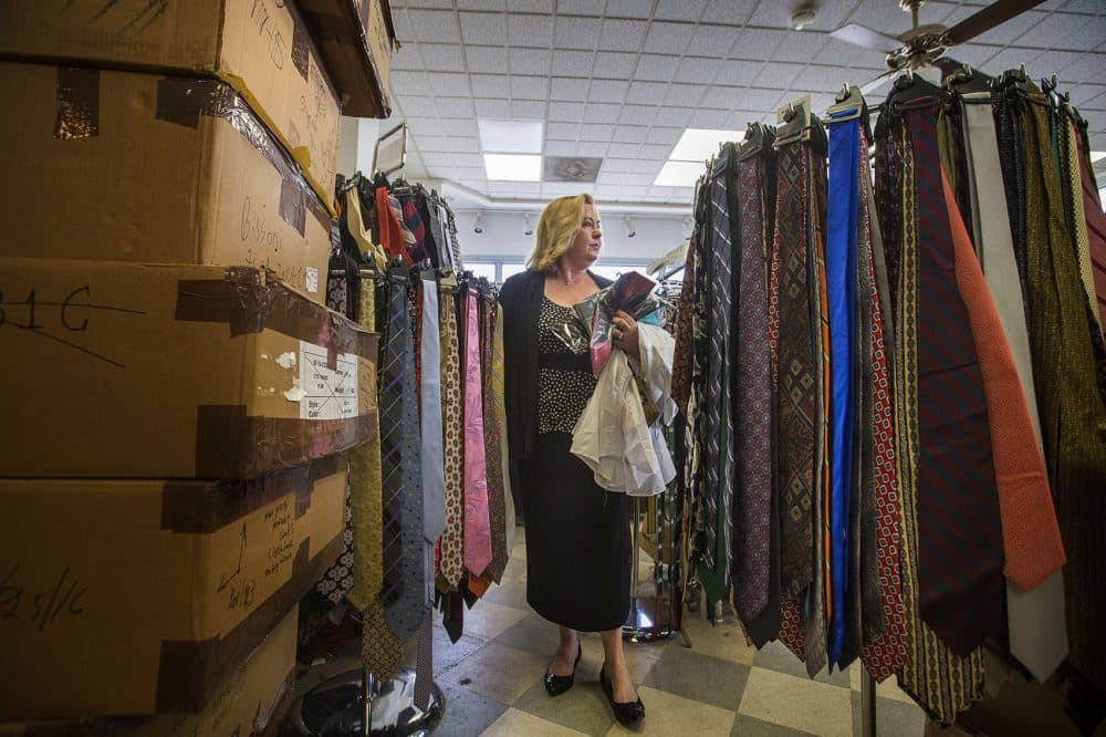 Kathy Seaman makes her way through tie racks and piles of boxes looking for formal wear for residents at a senior home in Jamaica Plain. (Jesse Costa/WBUR)