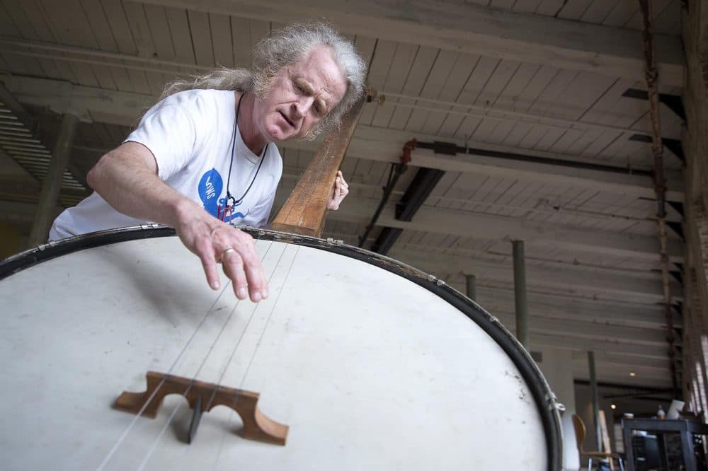 Musician Mark Stewart plays a 9-foot banjo created by Gunnar Schonbeck. (Robin Lubbock/WBUR)