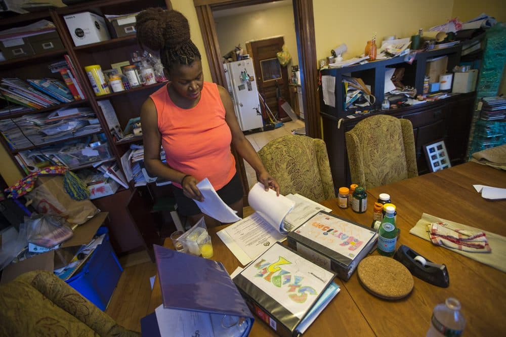 Hiliare sifts through a 100-plus-page binder that catalogs her son's diagnosis and communication with the school district. (Jesse Costa/WBUR)