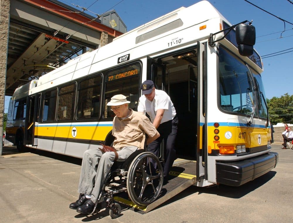 Jack Callinan, an instructor for MBTA bus operations, pushes Larry Braman of Cambridge, Mass., out of a low-floor, fully automated electric trolley bus after a news conference announcing the introduction of the new trolley buses Friday, June 4, 2004 at the MBTA's carhouse in Cambridge, Mass. The wheelchair accessible vehicles have modern accomodations such as air conditioning, automatic stop announcements and onboard visual displays depicting each stop. (AP Photo/Lisa Poole)