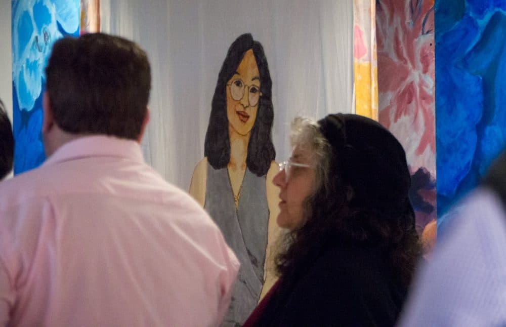 Visitors walk by a portrait by Wen Ti-Tsen at the opening of the Pao Arts Center. (Max Larkin/WBUR)