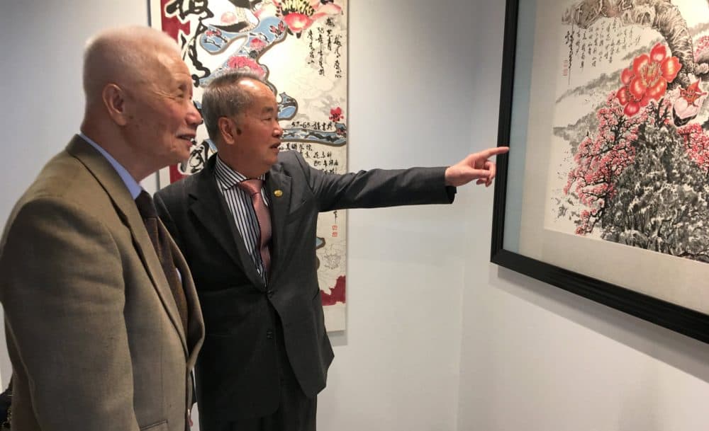 Mei Ching (right) and his cousin look at his painting, &quot;World of Flowers.&quot; (Max Larkin/WBUR)