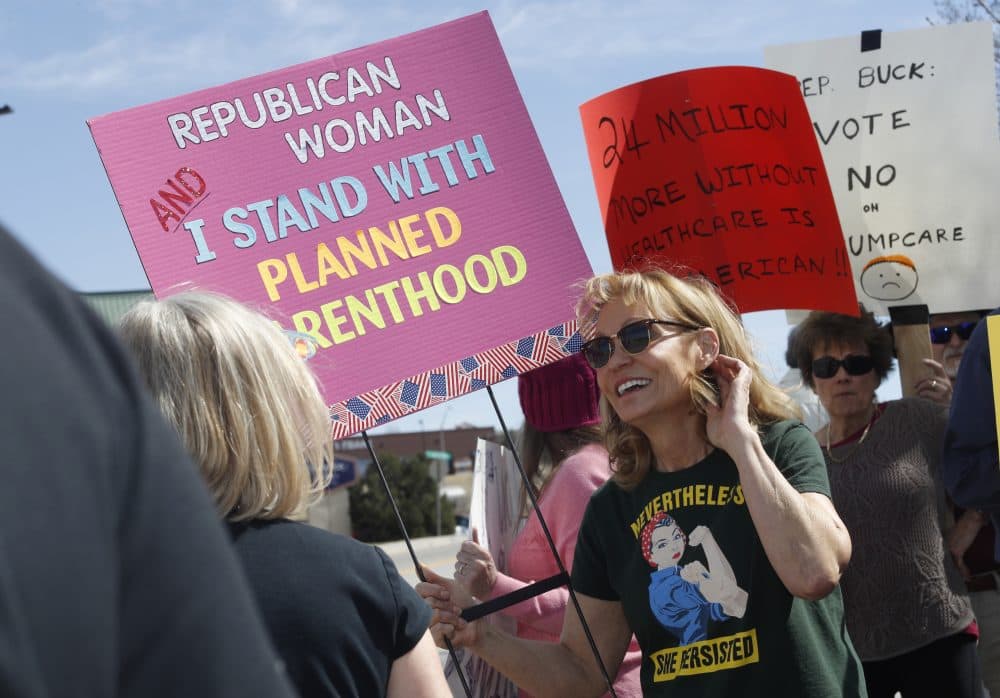 Carolyn Williamson waves a placard in support of Planned Parenthood in March 2017 as she joins other protesters against the failed Republican health care act outside the office of U.S. Rep. Ken Buck in Castle Rock, Colo. (David Zalubowski/AP)