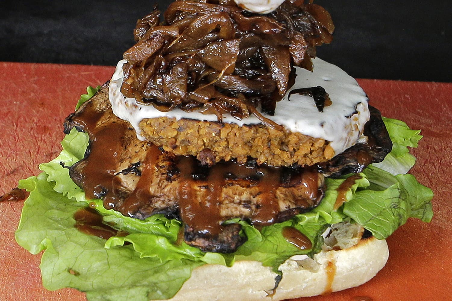 Caramelized onions are placed on a burger with blue cheese that sits on top of portobello mushroom and lettuce, during preparation of the Le Bleu hamburger, at the Atlas Meat-Free Delicatessen, in Miami. (Alan Diaz/AP)