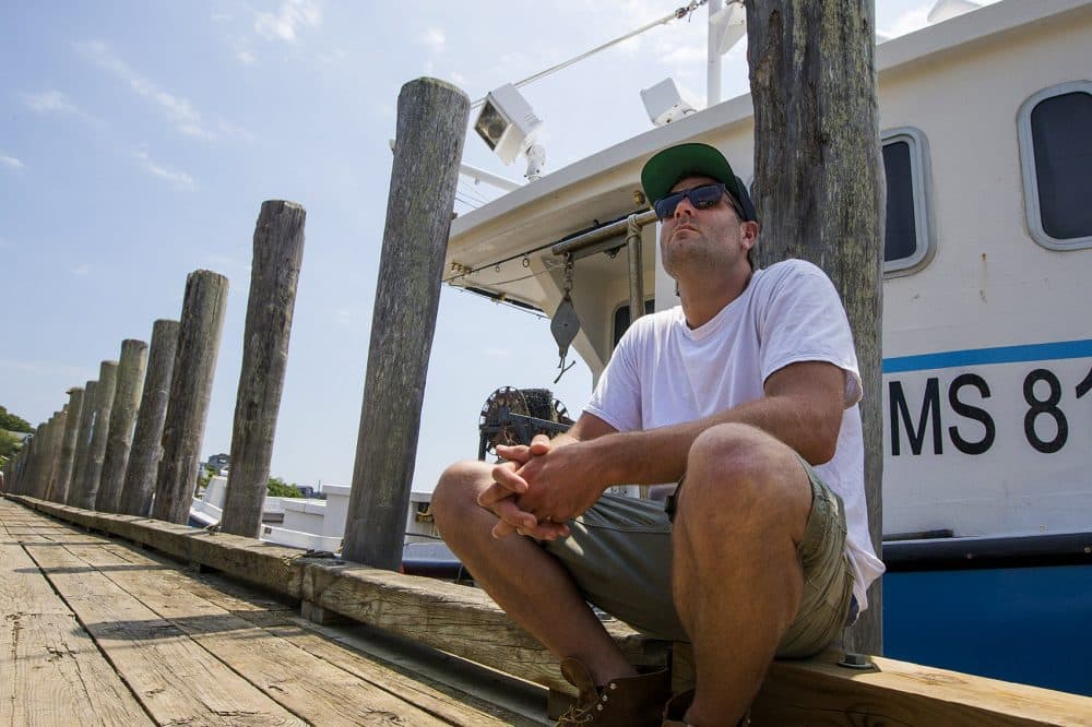 Fisherman Wes Brighton sits on Dutcher's Dock in Menemsha. (Jesse Costa/WBUR)