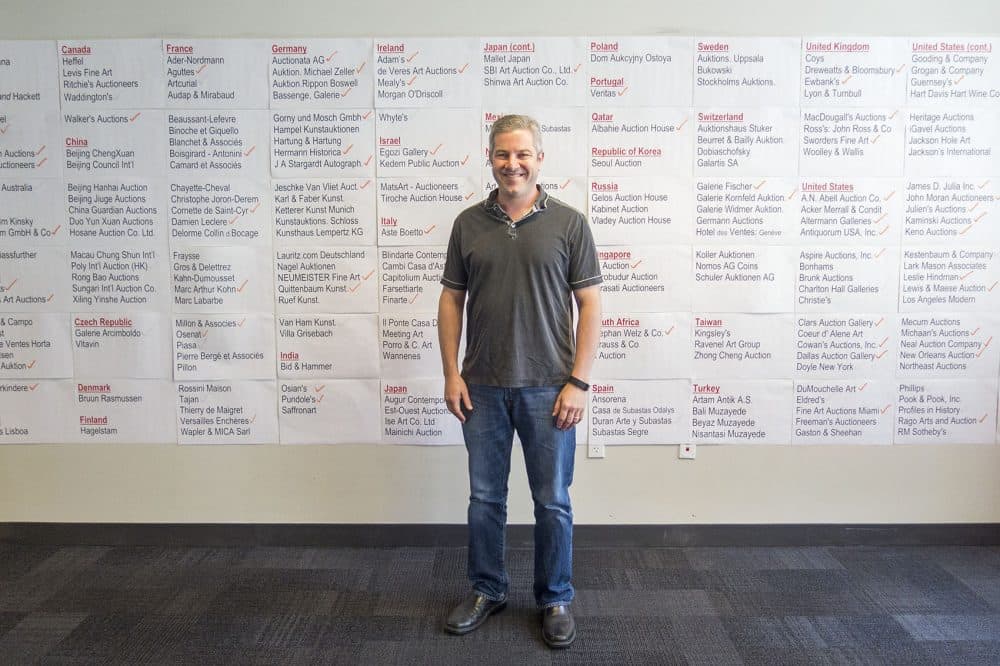Invaluable CEO Rob Weisberg stands in front of a wall at his office showing the geographic reach of auction houses that have singed on to the e-commerce site. (Andrea Shea/WBUR)