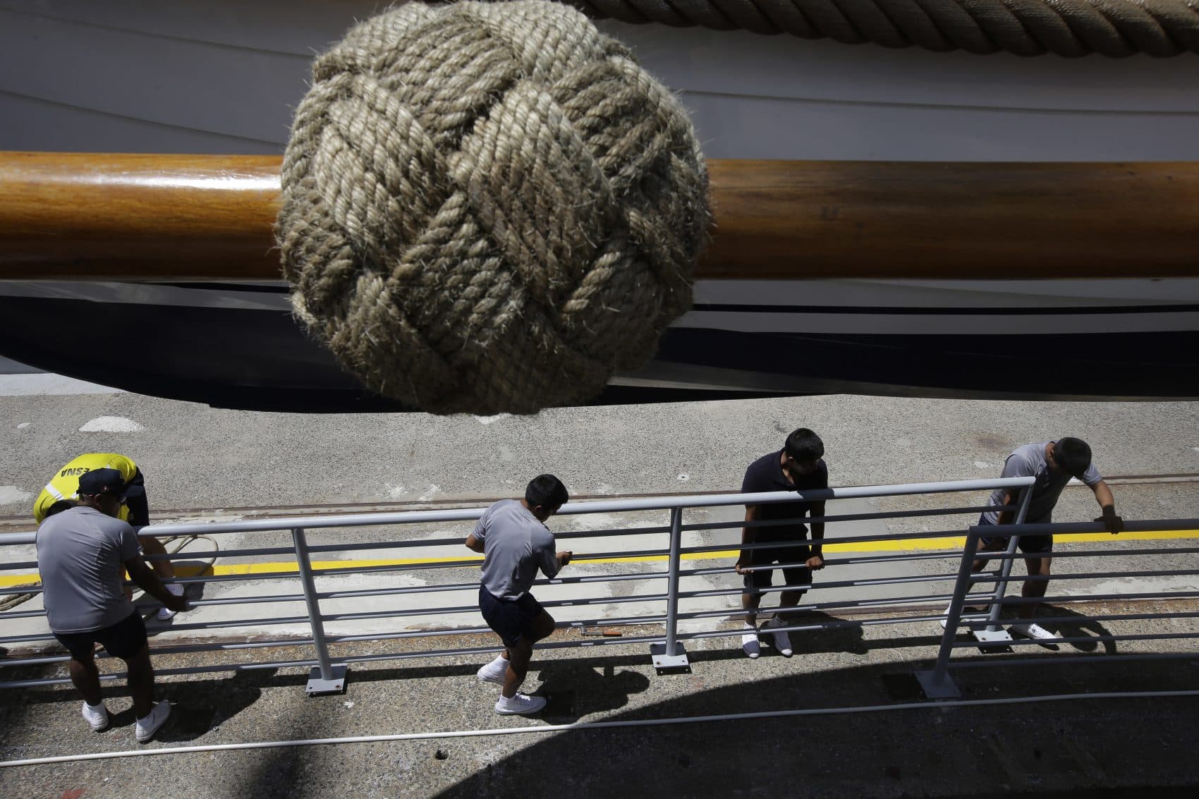 Crew members of the Peruvian Navy tall ship Union place a barrier on a dock near the vessel as the Union is docked in Boston Harbor on Sunday. (Steven Senne/AP)