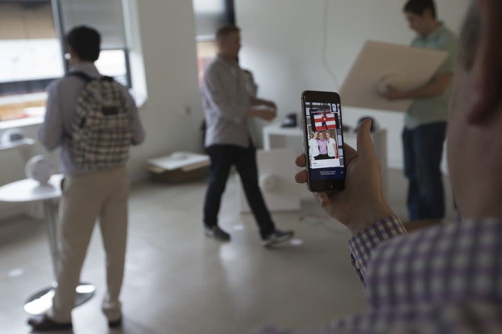 AFFOA CEO Yoel Fink plays a Bruce Springsteen song from the information that is stored in the fiber of a JanSport backpack using the AFFOA Looks app on his smartphone. (Jesse Costa/WBUR)