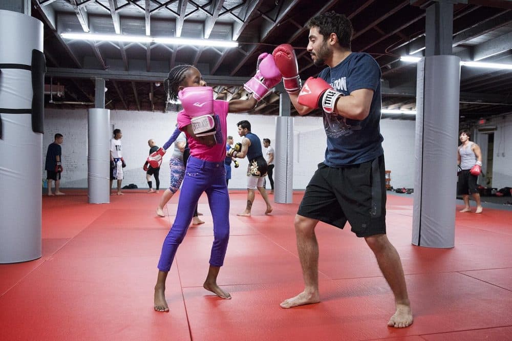 Vehari Brade, 8, tries out a punch on Fredy Melo. (Robin Lubbock/WBUR)