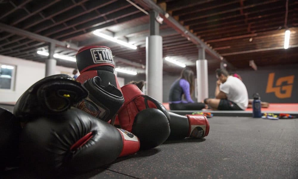 After an evening of sparring, a pile of gloves rests beside the mat at the Level Ground Mixed Martial Arts training center. (Robin Lubbock/WBUR)