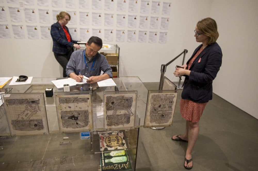 Goetschius stands and waits for her documentation to be filled out as part of the interactive &quot;Naturalization Drawing Table.&quot; (Jesse Costa/WBUR)