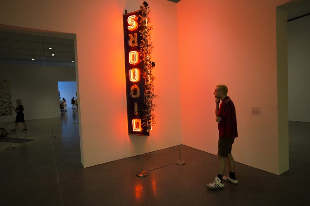 A man views the neon sign &quot;Radha Liquorsoul.&quot; (Jesse Costa/WBUR)