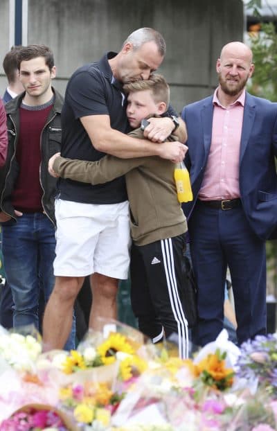 A man hugs a boy as they look at flowers near London Bridge on Monday. (Isabel Infantes/AP)
