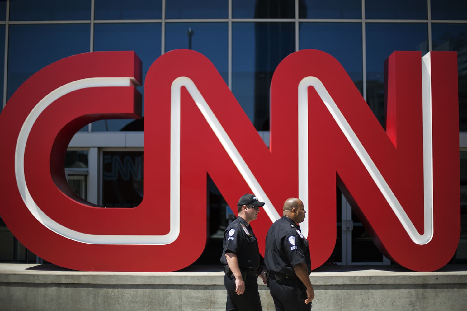 In this Aug. 26, 2014 file photo, security guards walk past the entrance to CNN headquarters in Atlanta. (David Goldman, File/AP)