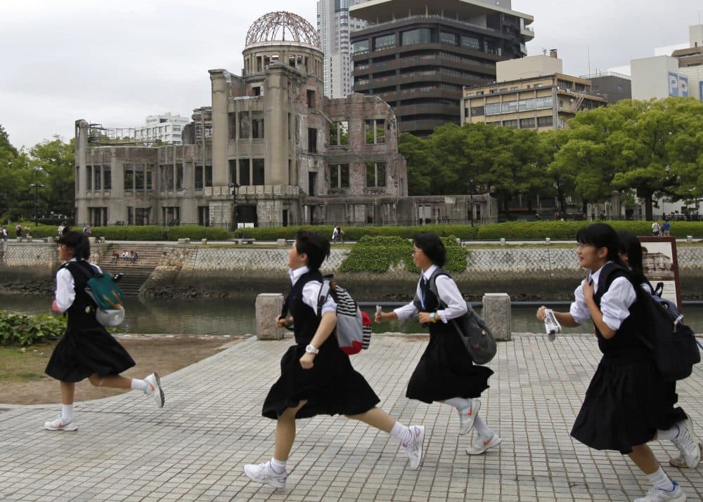 Schoolgirls run past the Atomic Bomb Dome at the Hiroshima Peace Memorial Park in Hiroshima, May 26, 2016. (Shuji Kajiyama/AP)