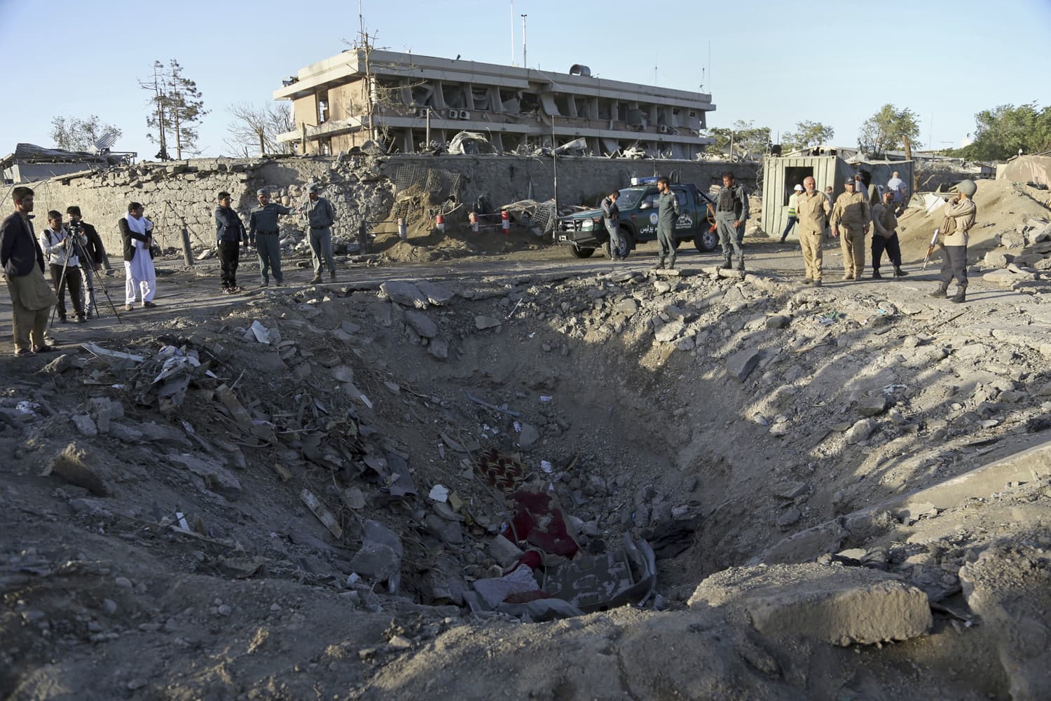 Security forces stand next to a crater created by massive explosion in front of the German Embassy in Kabul, Afghanistan, Wednesday, May 31, 2017. The suicide truck bomb hit a highly secure diplomatic area of Kabul killing scores of people and wounding hundreds more. (AP Photo/Rahmat Gul)
